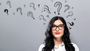 Question marks with young businesswoman. thinking of questions to ask her clients.